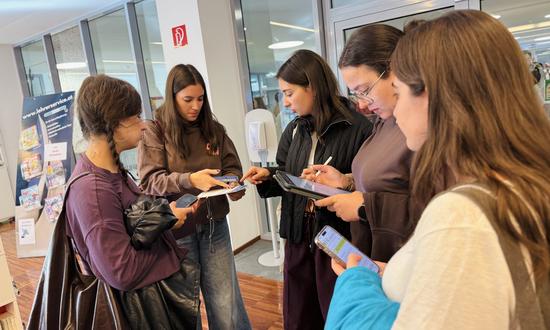 Studierende stehen in der Gruppe zusammen und studieren Informationen