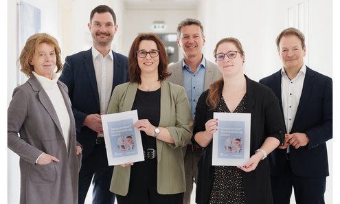 3 Frauen und 3 Männer blicken stehend in die Kamera. 2 Frauen halten eine Broschüre