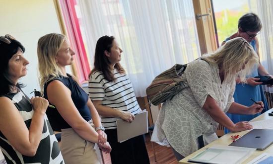 Frauen stehen verteilt vor einem Tisch, um sich in eine Liste einzutragen