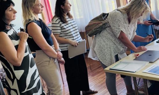 Frauen stehen verteilt vor einem Tisch, um sich in eine Liste einzutragen