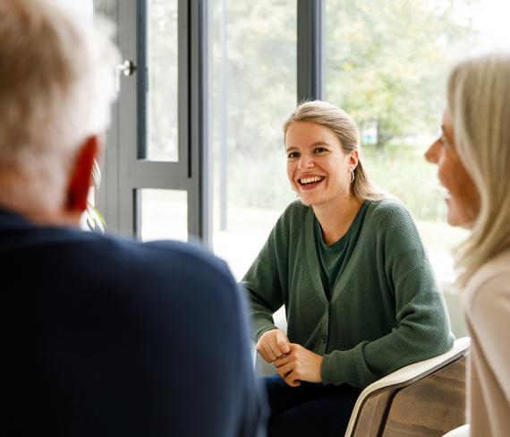 Drei Personen sitzen einander gegenüber und lachen