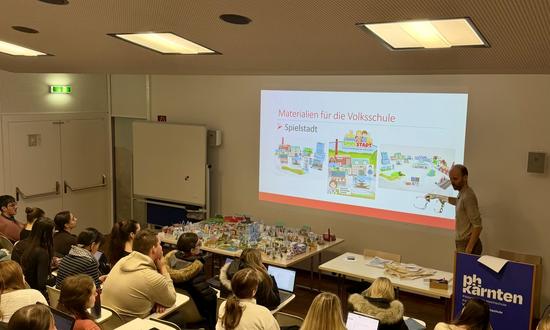 Blick von hinten in einem gefüllten Hörsaal auf die Bühne