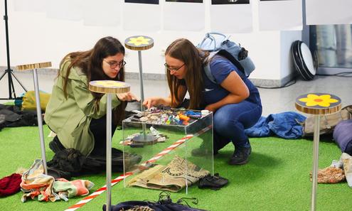 Zwei junge Frauen sehen sich Ausstellungsobjekte am Boden an