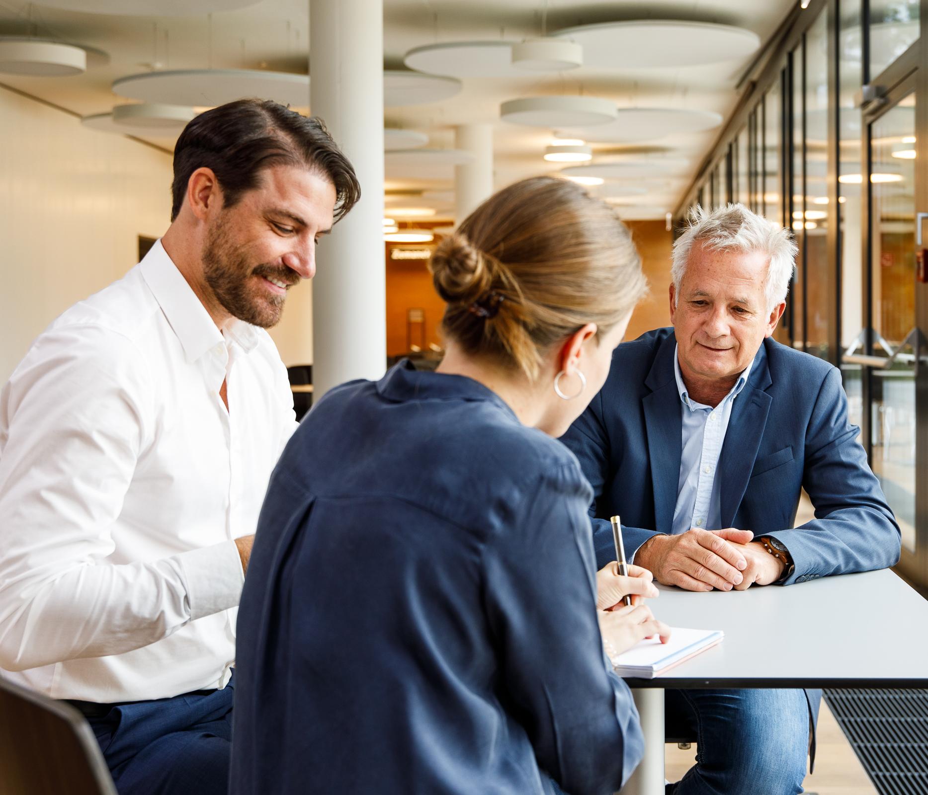 Drei Erwachsene im Dialog an einem Tisch