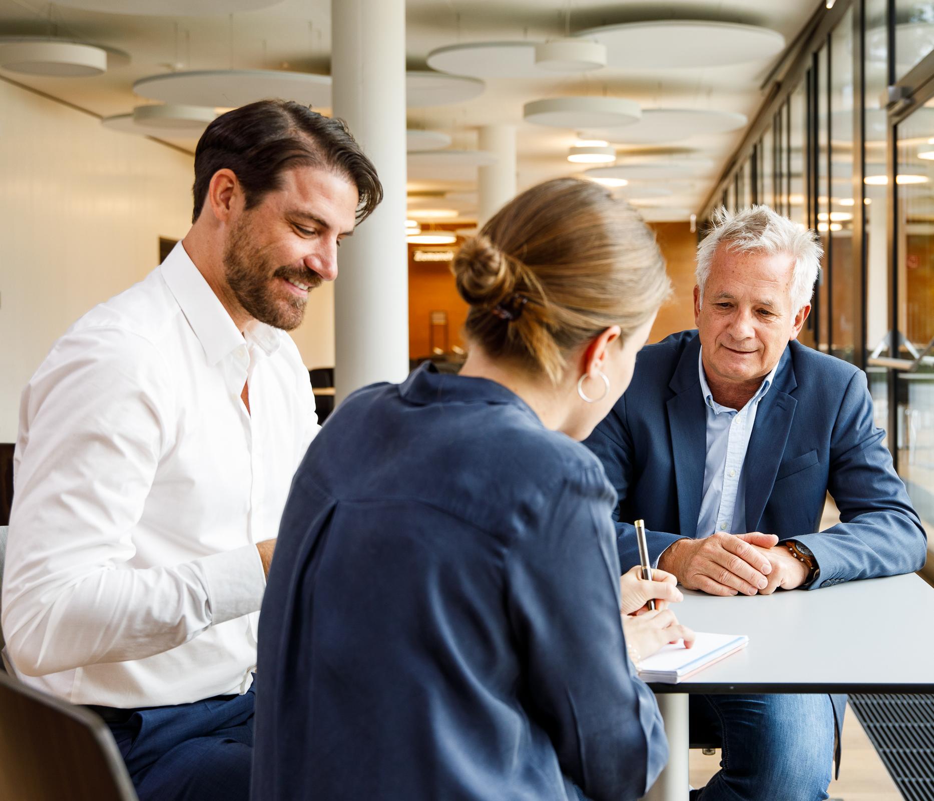 Beratung unter drei Kolleg:innen an einem Tisch