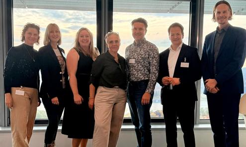 3 Frauen und 4 Männer blicken nebeneinander stehend in die Kamera