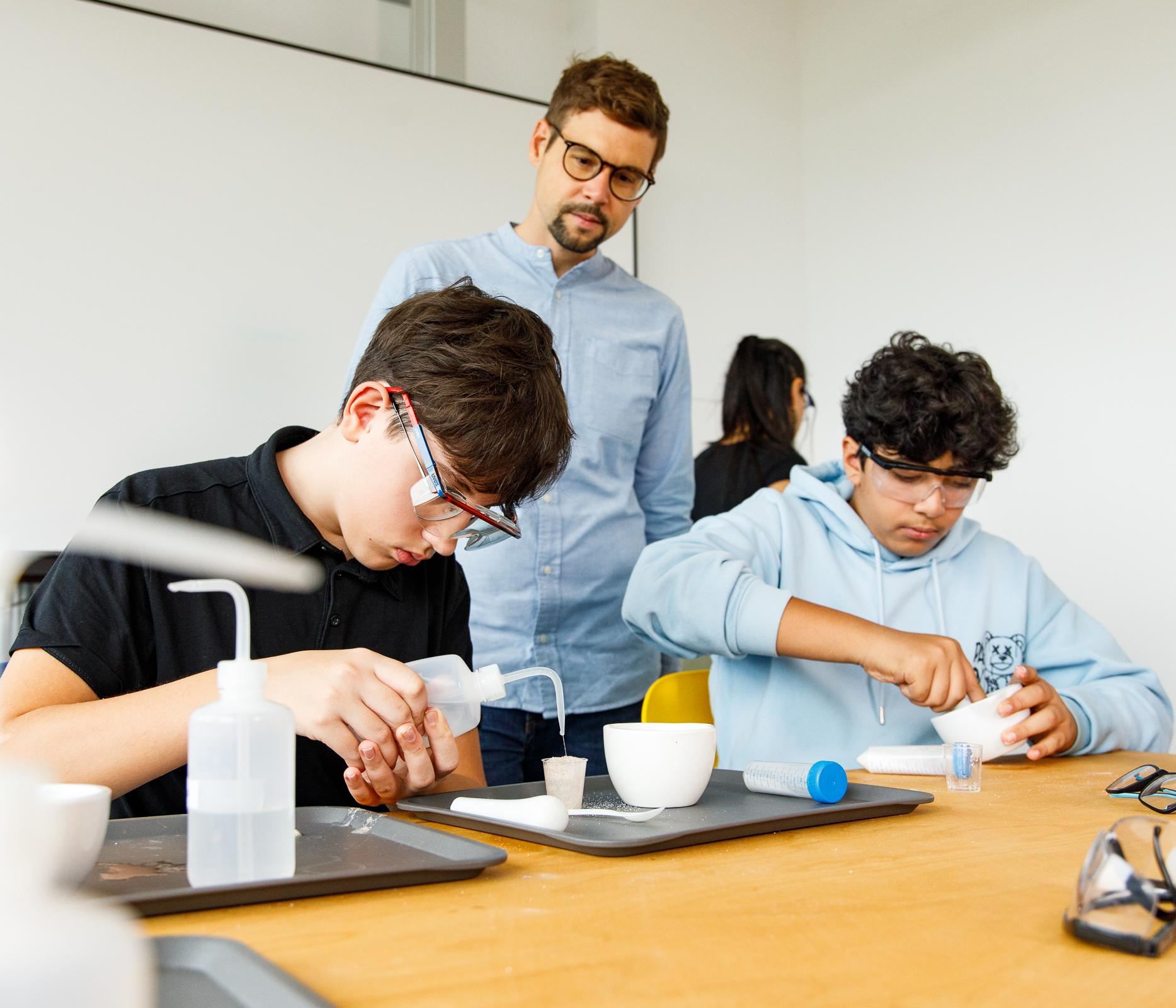 Zwei Schüler mit Lehrer im praktischen Unterricht