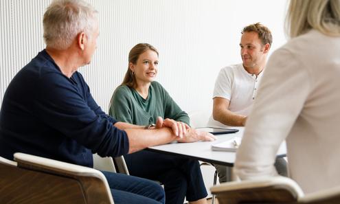 1 Frau und 3 Männer sitzen an einem Tisch und reden