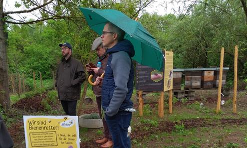 3 Männer stehen im Regen und richten ihren Blick in dieselbe Richtung