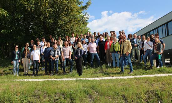 Gruppenbild der Teilnehmer: eine Menschenmenge steht auf einer Wiese vor dem Lakeside Park