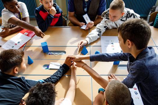 Kinder der Volksschule sitzen gemeinsam an einem Tisch und arbeiten